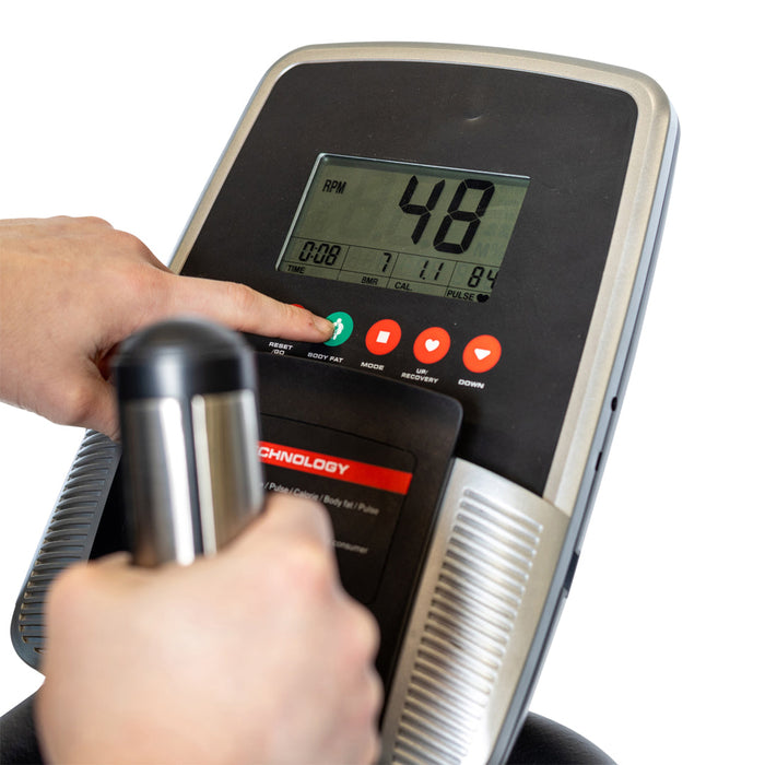 Close-up of a hand pressing a green button on the Bells of Steel Blitz Stepper's control panel, with a digital display showing workout info and another hand gripping the handle for effective low-impact cardio.