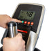 Close-up of a hand pressing a green button on the Bells of Steel Blitz Stepper's control panel, with a digital display showing workout info and another hand gripping the handle for effective low-impact cardio.